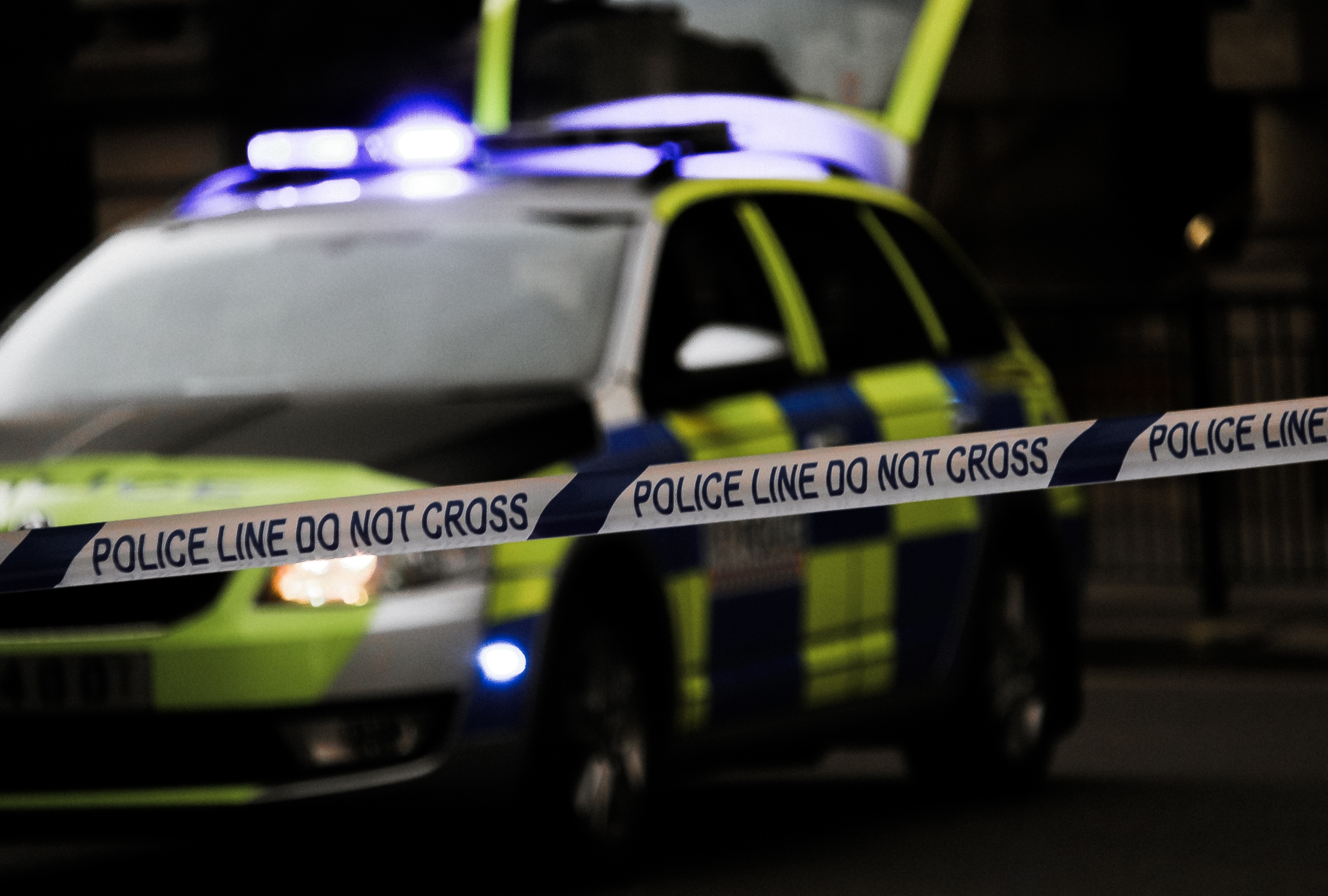 Police car behind tape stating "police line do not cross".